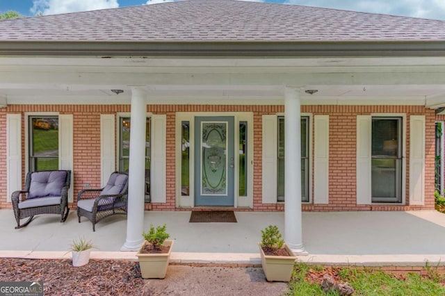 2005 Ashton Pointe Dr, Dacula, GA 30019 - view of exterior entry with covered porch, roof with shingles, and brick siding