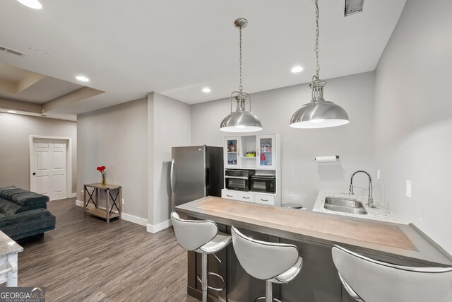 2995 Barimore Pl, Dacula, GA 30019 - kitchen featuring freestanding refrigerator, dark wood-type flooring, a peninsula, a breakfast bar area, and light countertops