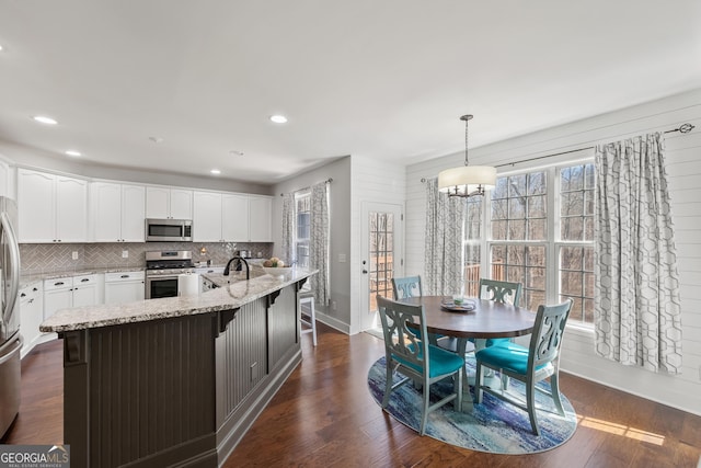 2995 Barimore Pl, Dacula, GA 30019 - kitchen featuring appliances with stainless steel finishes, light stone counters, a chandelier, white cabinetry, and decorative backsplash