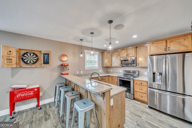2717 Old Eastman Rd, Cadwell, GA 31009 - kitchen featuring stainless steel appliances, a peninsula, light wood finished floors, light stone counters, and a kitchen bar