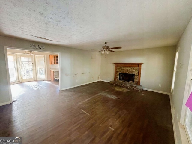 43 Oak Landing Cir, Douglasville, GA 30134 - unfurnished living room with dark wood-style flooring, a ceiling fan, a stone fireplace, and a textured ceiling