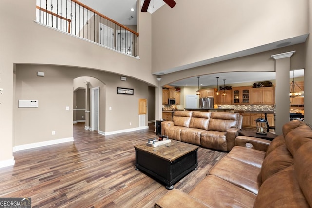 149 Highland Rd S, Dahlonega, GA 30533 - living area with arched walkways, ceiling fan, a high ceiling, wood finished floors, and baseboards