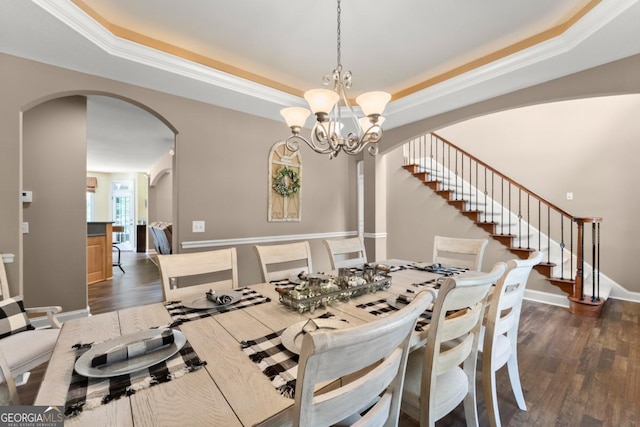 149 Highland Rd S, Dahlonega, GA 30533 - dining room featuring arched walkways, a tray ceiling, dark wood-type flooring, stairs, and a chandelier