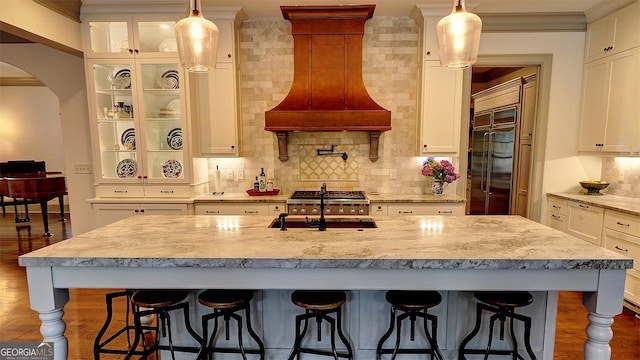 1178 Chambord Way NE, Brookhaven, GA 30319 - kitchen with custom exhaust hood, wood finished floors, backsplash, glass insert cabinets, and crown molding