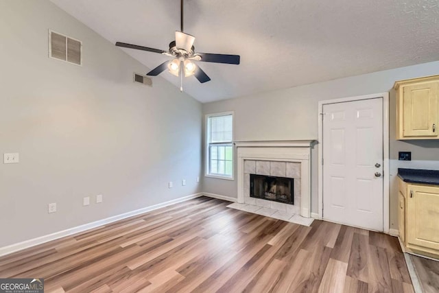 275 Mountain Way, Covington, GA 30016 - unfurnished living room featuring lofted ceiling, a ceiling fan, light wood finished floors, and a tile fireplace