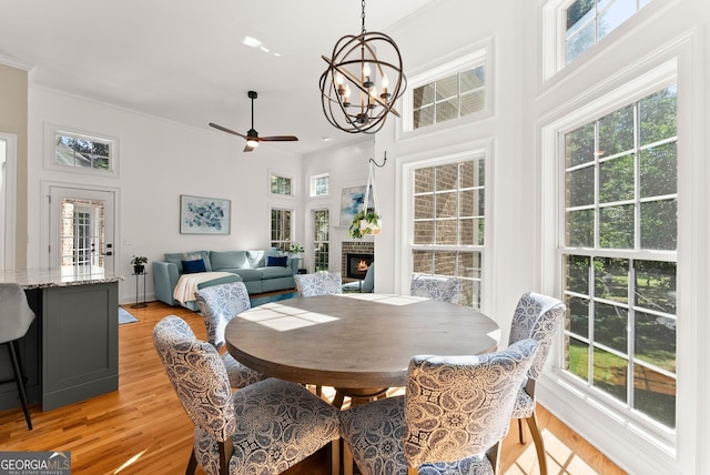 1421 Lane Creek Dr, Bishop, GA 30621 - dining room with ornamental molding, light wood-style flooring, a warm lit fireplace, ceiling fan, and a chandelier