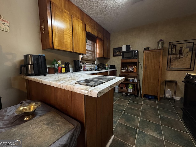 114 Hope Pl, Warner Robins, GA 31088 - kitchen with brown cabinetry, a peninsula, black microwave, a textured ceiling, and cooktop