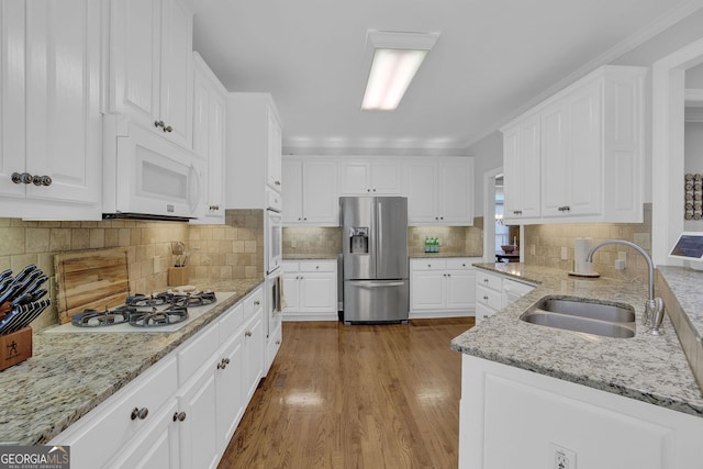 1304 Swallows Walk, Grayson, GA 30017 - kitchen featuring white appliances, a sink, white cabinets, wood finished floors, and tasteful backsplash