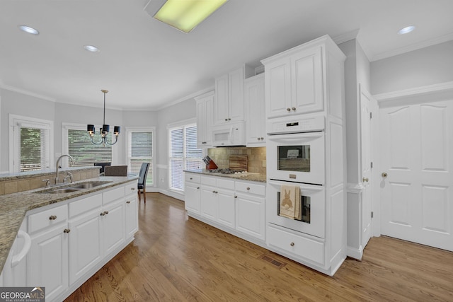 1304 Swallows Walk, Grayson, GA 30017 - kitchen with white appliances, crown molding, light wood-style floors, a chandelier, and white cabinetry