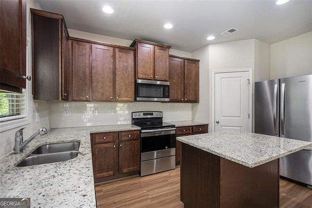 422 Dublin Way, Dallas, GA 30132 - kitchen with stainless steel appliances, a sink, light wood-style floors, a kitchen island, and backsplash