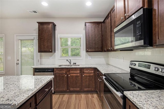 422 Dublin Way, Dallas, GA 30132 - kitchen featuring stainless steel appliances, a sink, light stone countertops, backsplash, and light wood finished floors