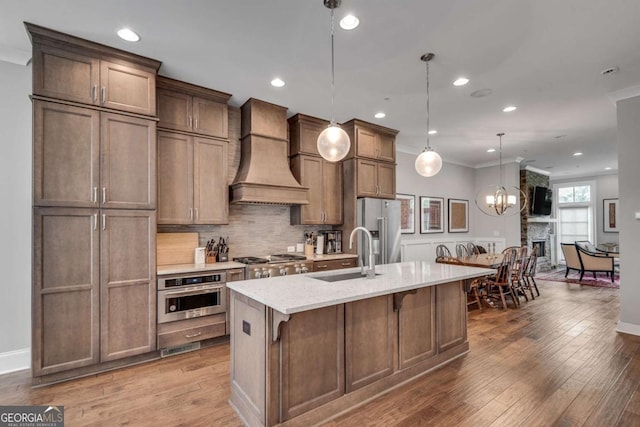 345 Glen Iris Dr NE Unit 3, Atlanta, GA 30312 - kitchen with appliances with stainless steel finishes, premium range hood, tasteful backsplash, a kitchen island with sink, and wood finished floors