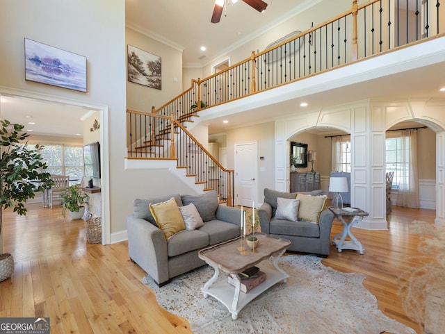 70 Baker Pond Ct, Jefferson, GA 30549 - living room with arched walkways, ceiling fan, crown molding, light wood-type flooring, and a towering ceiling