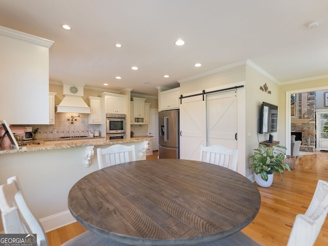 70 Baker Pond Ct, Jefferson, GA 30549 - dining room with a barn door, crown molding, recessed lighting, and light wood-style floors
