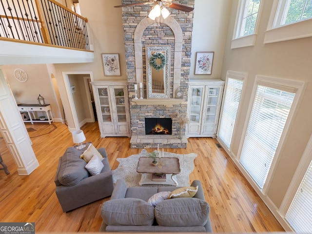 70 Baker Pond Ct, Jefferson, GA 30549 - living room featuring a high ceiling, ceiling fan, a stone fireplace, baseboards, and wood finished floors