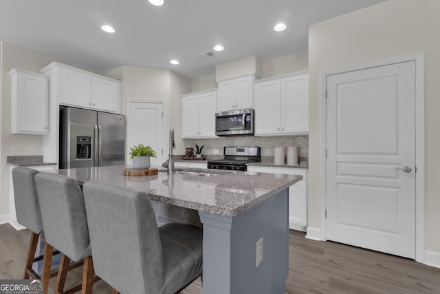 206 Roundwood Way, Peachtree City, GA 30269 - kitchen with stainless steel appliances, light stone countertops, wood finished floors, a kitchen breakfast bar, and recessed lighting