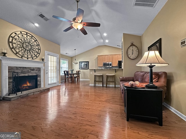 118 Hunterian Pl, Newnan, GA 30265 - living area with vaulted ceiling, ceiling fan, wood finished floors, baseboards, and a stone fireplace
