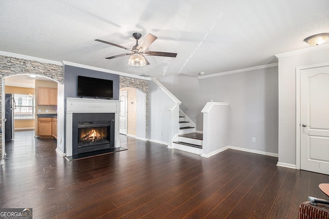3262 Cascade Parc Blvd SW, Atlanta, GA 30311 - unfurnished living room featuring ceiling fan, arched walkways, a textured ceiling, stairs, and a warm lit fireplace