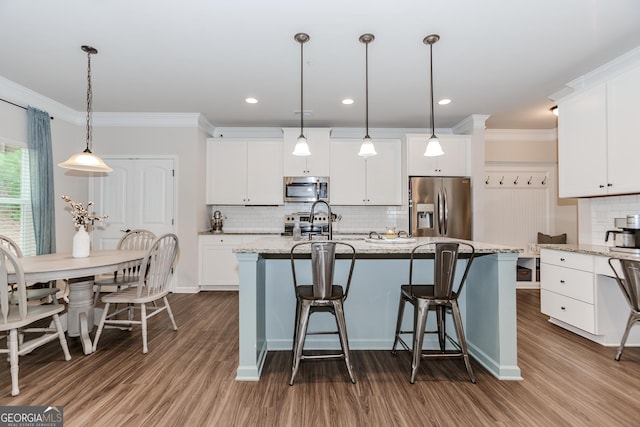 1243 Glenville Ct, Hoschton, GA 30548 - kitchen with appliances with stainless steel finishes, dark wood-type flooring, decorative backsplash, a center island with sink, and crown molding