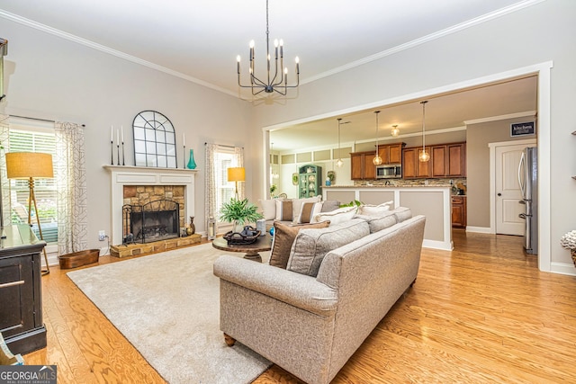 172 Walden Pond Trl, Senoia, GA 30276 - living room featuring light wood-style floors, crown molding, a chandelier, a stone fireplace, and baseboards