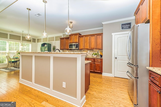 172 Walden Pond Trl, Senoia, GA 30276 - kitchen featuring stainless steel appliances, light wood-style flooring, ornamental molding, an island with sink, and pendant lighting