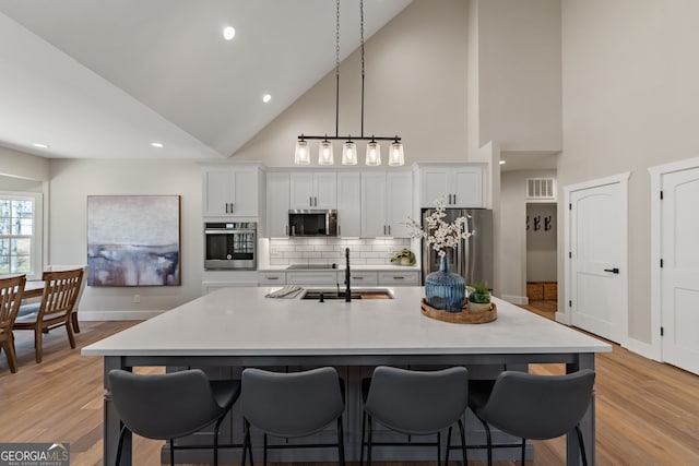 219 Fairview Dr, Morganton, GA 30560 - kitchen featuring appliances with stainless steel finishes, a kitchen island with sink, a kitchen bar, high vaulted ceiling, and light countertops