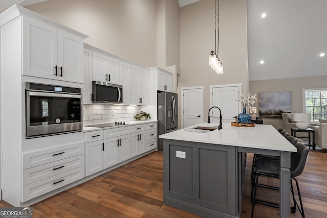 219 Fairview Dr, Morganton, GA 30560 - kitchen with appliances with stainless steel finishes, high vaulted ceiling, an island with sink, white cabinets, and backsplash
