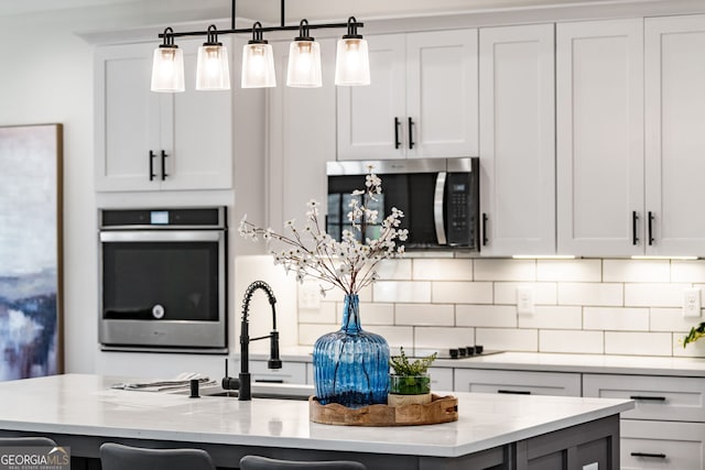 219 Fairview Dr, Morganton, GA 30560 - kitchen with appliances with stainless steel finishes, backsplash, a kitchen island with sink, and light stone counters