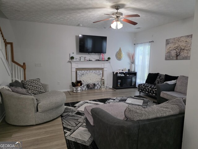 10315 Whisper Glen Dr, Midland, GA 31820 - living area with stairs, wood finished floors, a fireplace, ceiling fan, and a textured ceiling