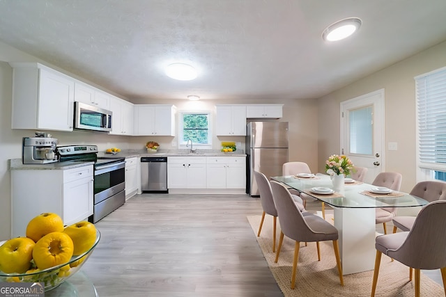 4457 Lincoln Jones Rd, Ellenwood, GA 30294 - kitchen featuring appliances with stainless steel finishes, a sink, light wood-style flooring, and white cabinets