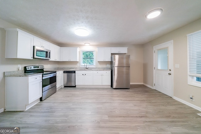 4457 Lincoln Jones Rd, Ellenwood, GA 30294 - kitchen with stainless steel appliances, a sink, white cabinets, baseboards, and light stone counters