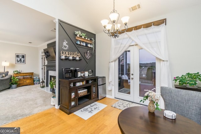 271 Double Gate Ct, Sugar Hill, GA 30518 - living room with a chandelier, wood finished floors, a fireplace with flush hearth, ornamental molding, and french doors