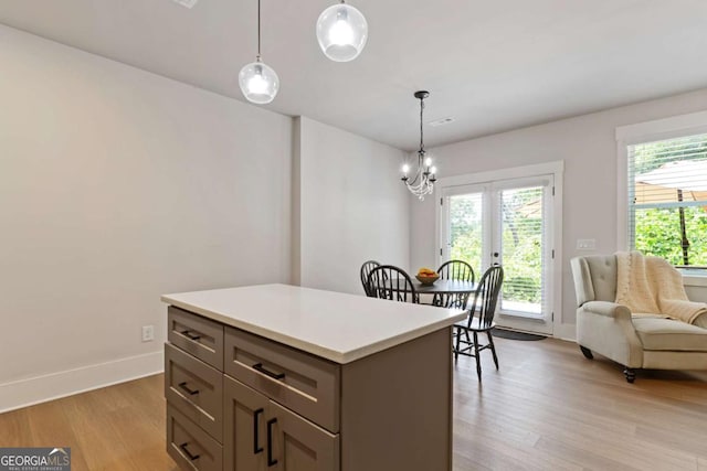 4110 Gentle Breeze Way, Braselton, GA 30517 - kitchen with light wood-style flooring, light countertops, a chandelier, a center island, and decorative light fixtures