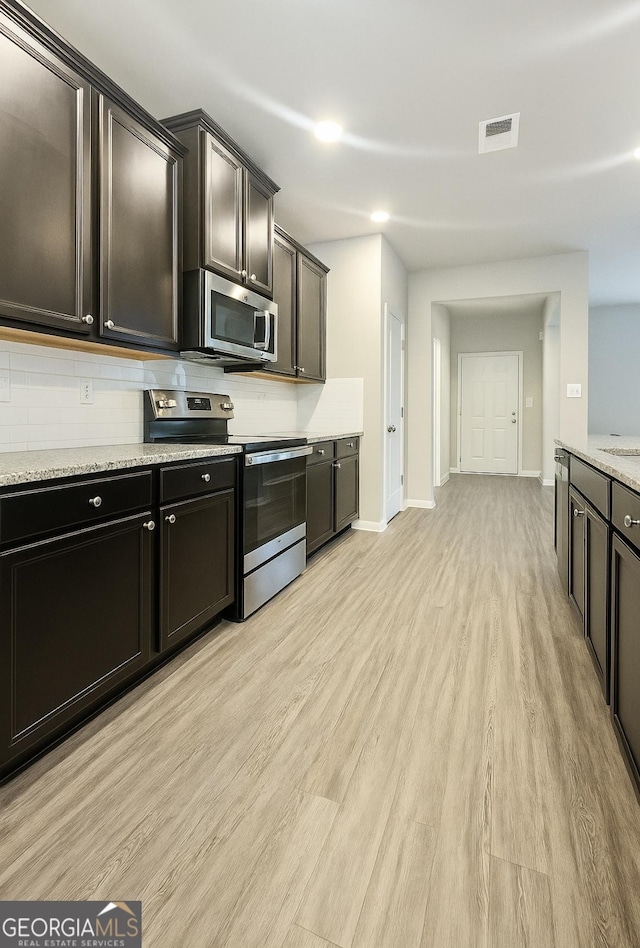 1317 Rosemary Ln # 65, East Point, GA 30344 - kitchen with stainless steel appliances, light wood-style flooring, decorative backsplash, and light stone counters