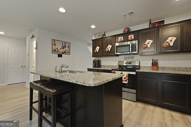 33 Easy St, Guyton, GA 31312 - kitchen with stainless steel appliances, a sink, light wood-type flooring, light stone counters, and an island with sink