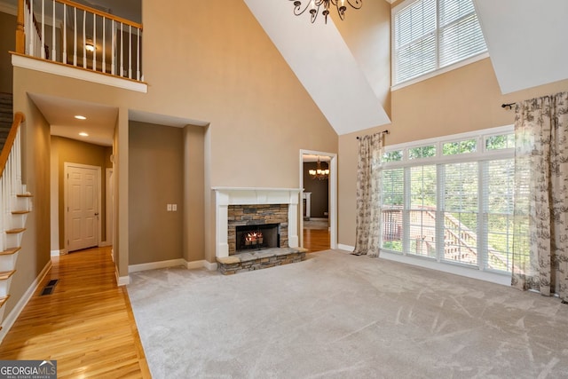 203 Crescent Moon Way, Canton, GA 30114 - unfurnished living room with a chandelier, a high ceiling, stairway, a stone fireplace, and baseboards