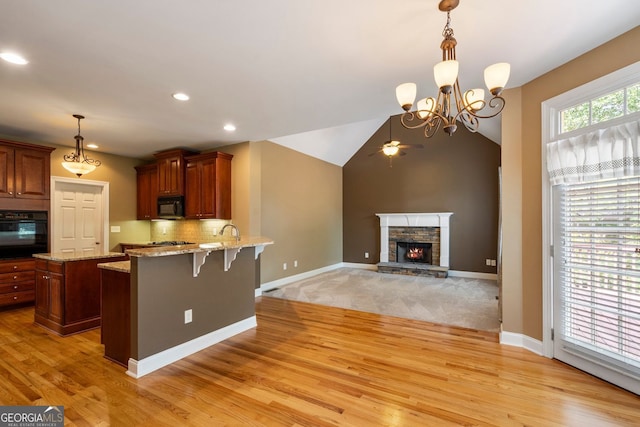 203 Crescent Moon Way, Canton, GA 30114 - kitchen with black appliances, a fireplace, light wood-style flooring, a peninsula, and recessed lighting