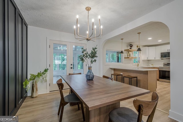 2825 Shea Way SW, Marietta, GA 30060 - dining area featuring arched walkways, light wood finished floors, a textured ceiling, a chandelier, and french doors