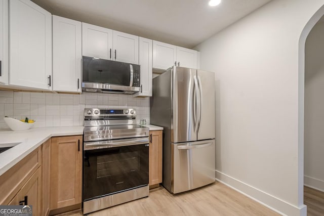 2825 Shea Way SW, Marietta, GA 30060 - kitchen with stainless steel appliances, light wood-type flooring, arched walkways, decorative backsplash, and light countertops