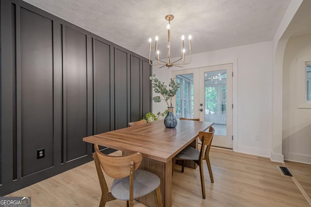 2825 Shea Way SW, Marietta, GA 30060 - dining room with a chandelier, light wood-type flooring, baseboards, a textured ceiling, and arched walkways