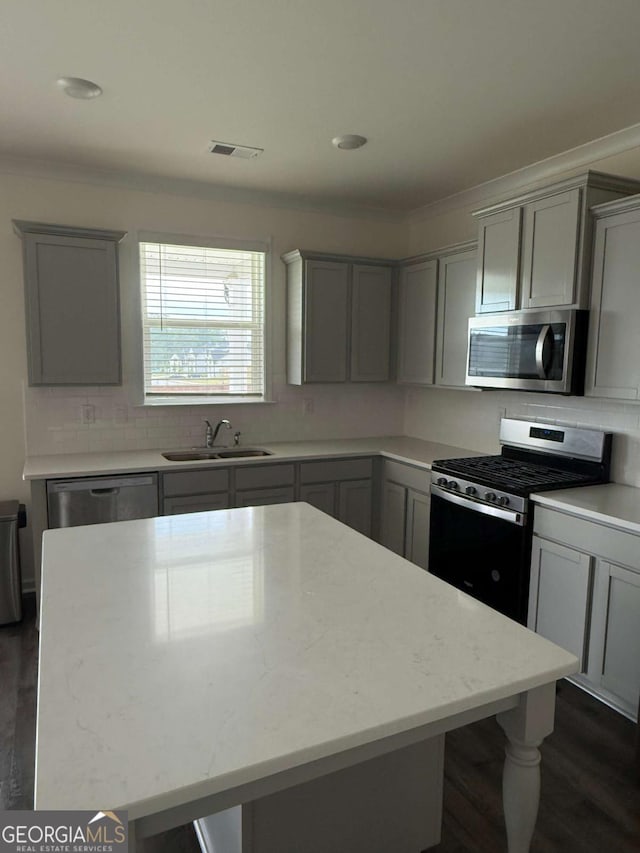 3378 English Elm Way, Loganville, GA 30052 - kitchen with appliances with stainless steel finishes, a sink, gray cabinets, dark wood-type flooring, and tasteful backsplash