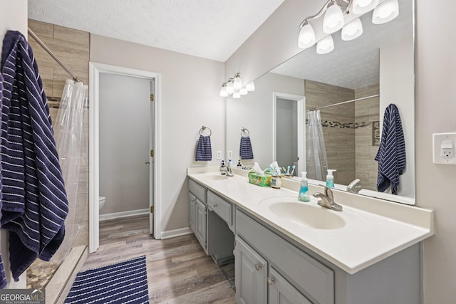 130 Emerald Dr, Mcdonough, GA 30253 - bathroom with double vanity, wood finished floors, tiled shower, and a textured ceiling