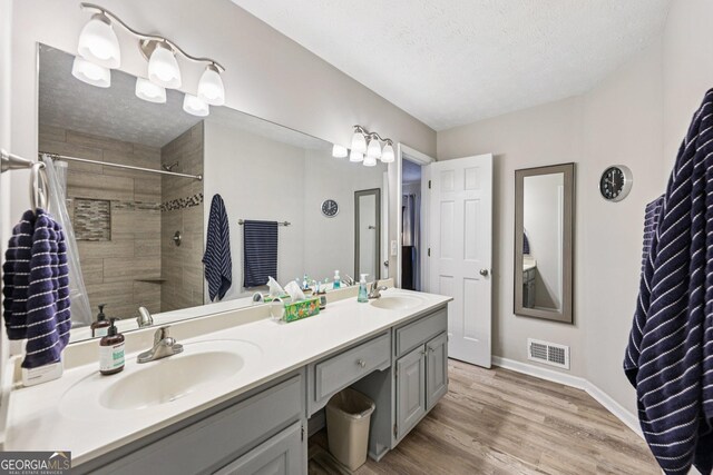 130 Emerald Dr, Mcdonough, GA 30253 - bathroom with double vanity, wood finished floors, a tile shower, and a textured ceiling