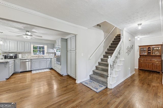 130 Emerald Dr, Mcdonough, GA 30253 - kitchen with appliances with stainless steel finishes, gray cabinetry, wood finished floors, decorative backsplash, and ceiling fan