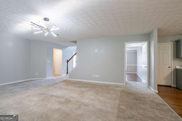 2482 Brittany Park Ln, Ellenwood, GA 30294 - carpeted empty room with stairway, baseboards, and a textured ceiling