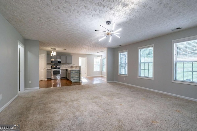 2482 Brittany Park Ln, Ellenwood, GA 30294 - unfurnished living room featuring a chandelier, baseboards, dark carpet, and a textured ceiling