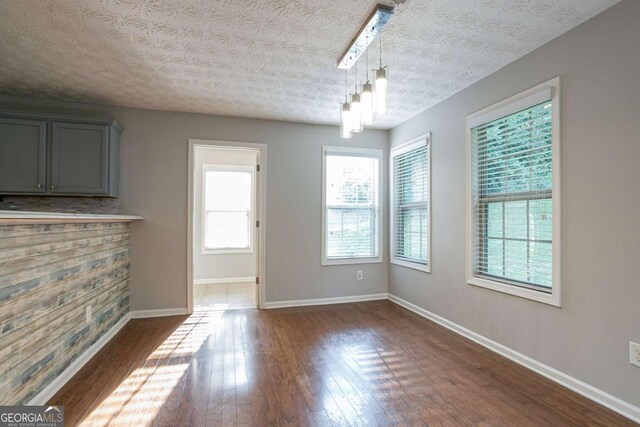 2482 Brittany Park Ln, Ellenwood, GA 30294 - unfurnished dining area featuring dark wood finished floors, a textured ceiling, and baseboards