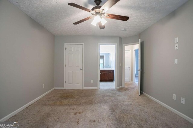 2482 Brittany Park Ln, Ellenwood, GA 30294 - unfurnished bedroom featuring a textured ceiling, baseboards, light carpet, and ensuite bath