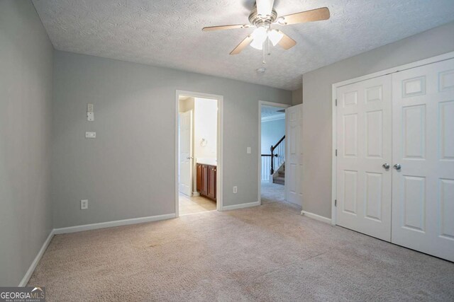 2482 Brittany Park Ln, Ellenwood, GA 30294 - unfurnished bedroom featuring light colored carpet, a textured ceiling, baseboards, a closet, and ceiling fan