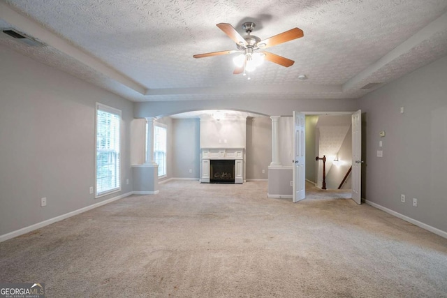 2482 Brittany Park Ln, Ellenwood, GA 30294 - unfurnished living room featuring a fireplace, ornate columns, light colored carpet, ceiling fan, and a textured ceiling